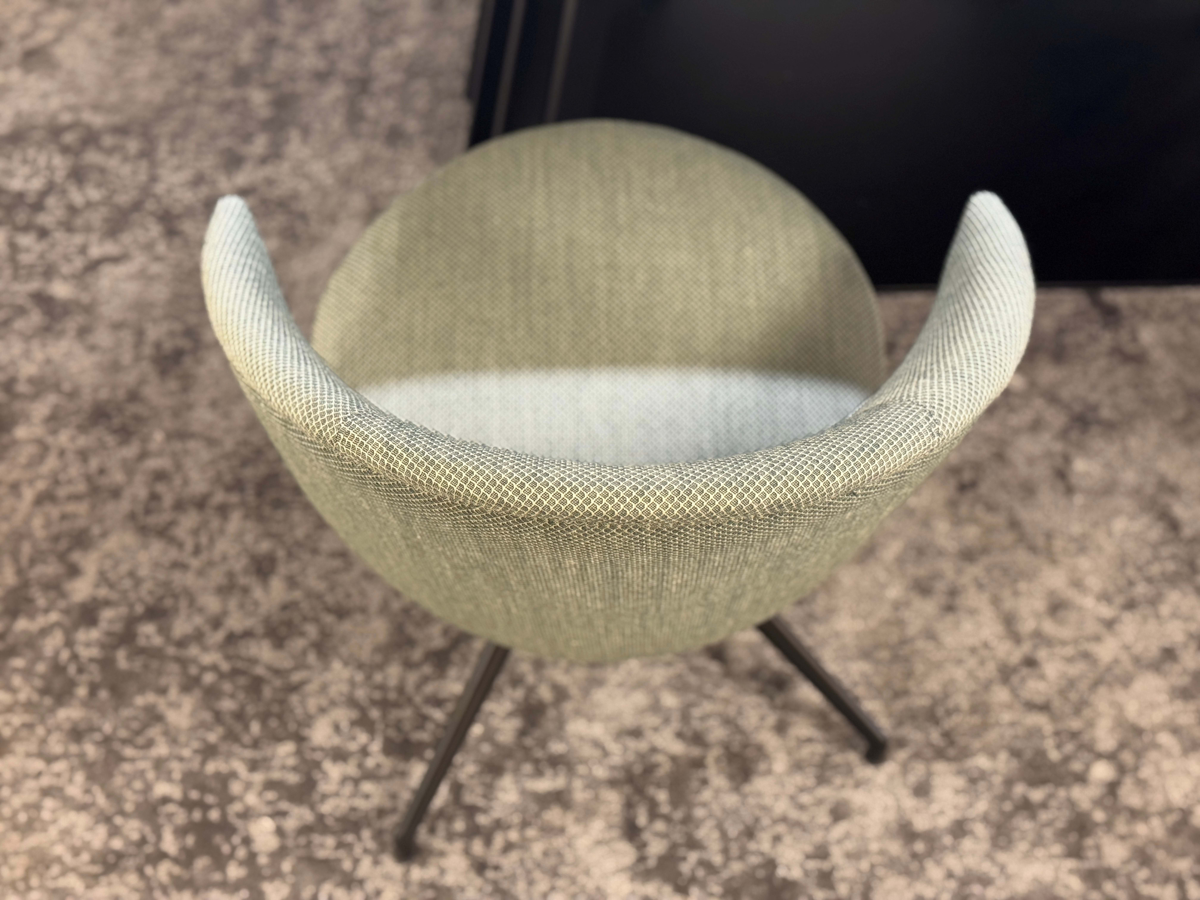 Vue de dessus de la chaise Willisau Loreo (copie), une chaise moderne en tissu vert clair avec des pieds en métal noir, posée sur un sol moucheté.