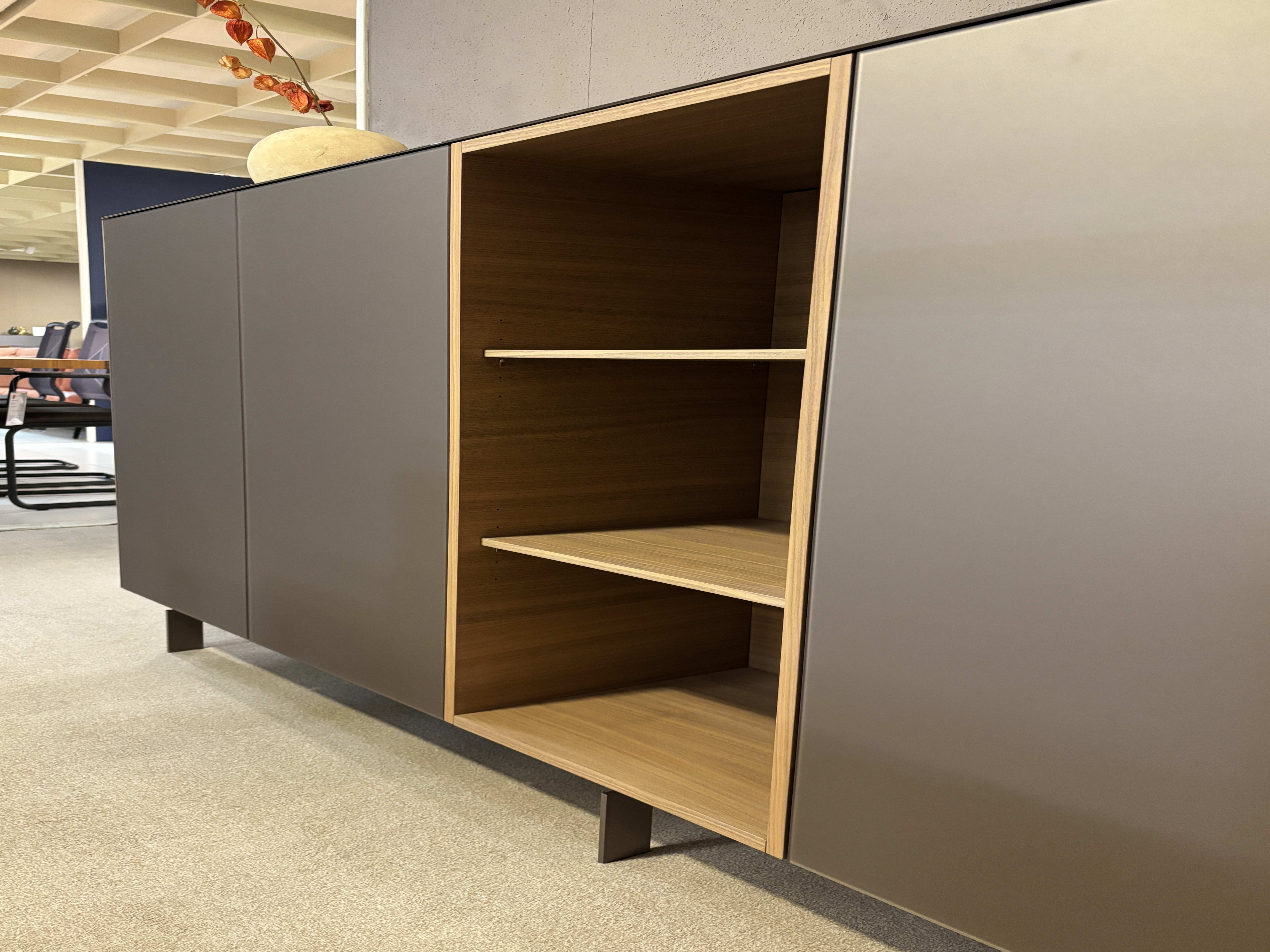 Le buffet Spectral de 250 cm possède des portes mates et foncées, une étagère en bois ouverte et des pieds en métal qui ajoutent une touche de modernité à n'importe quel bureau. Le buffet Spectral de 250 cm possède des portes mates et foncées, une étagère en bois ouverte et des pieds en métal qui ajoutent une touche de modernité à n'importe quel bureau.