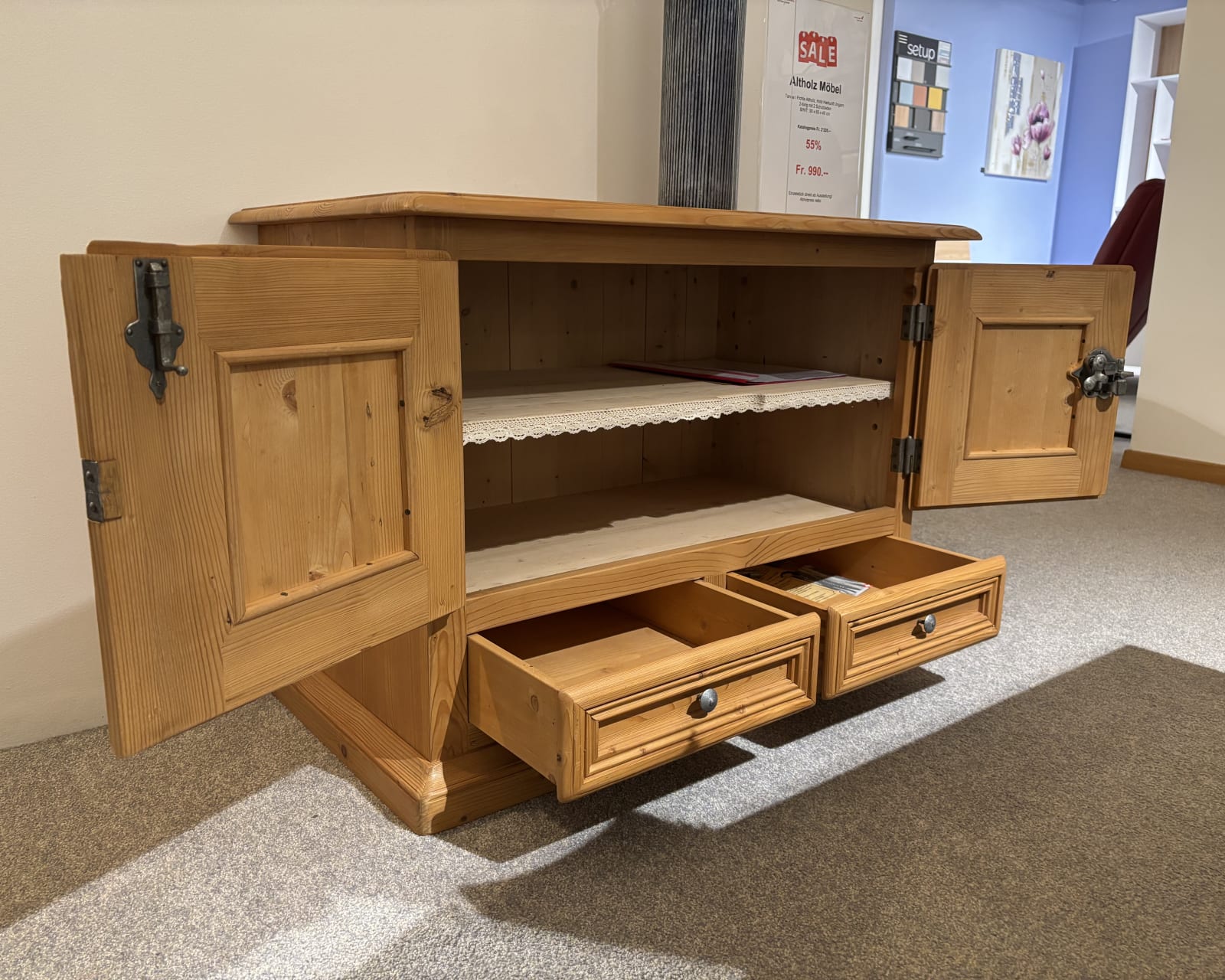 Das „Büromöbel mit 3 Boxen Window“ ist ein offener Holzschrank mit Türen und Schubladen und einem Regaleinsatz aus Spitzen. Es steht in einem mit Teppich ausgelegten Raum mit einem Verkaufsschild in der Nähe.