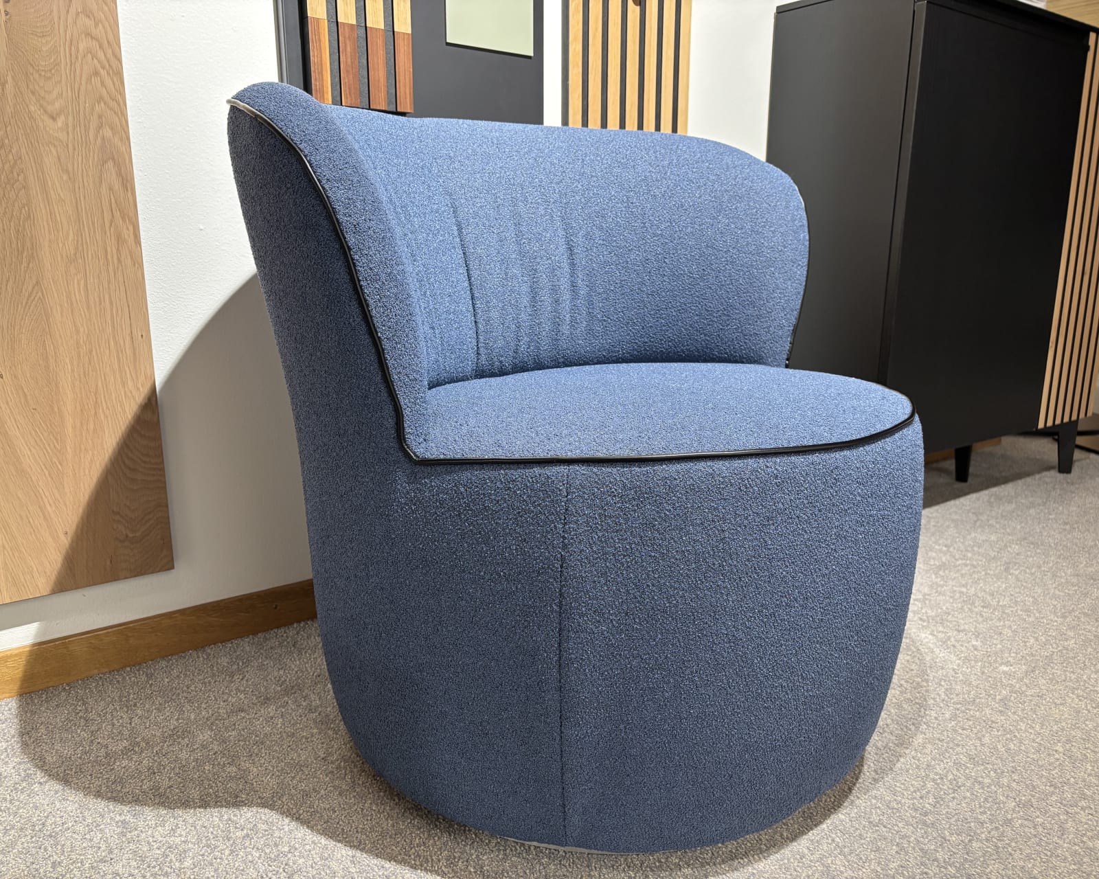 Ein Büromöbel mit 3 Boxen Window-Stuhl mit blauer Polsterung ergänzt einen Raum mit Holz und schwarzen Akzenten.