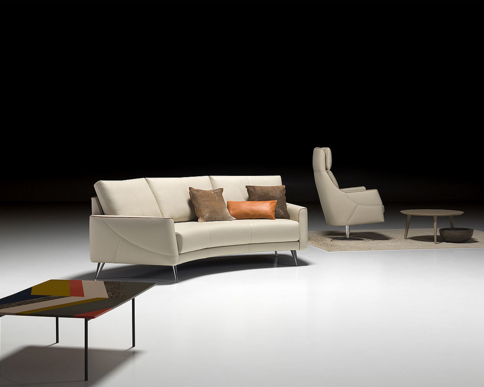 Modernes Wohnzimmer mit dem Sofa Thalia 9182 in Creme, ergänzt durch einen Sessel, einen Couchtisch und Akzentkissen auf einem weißen Boden.