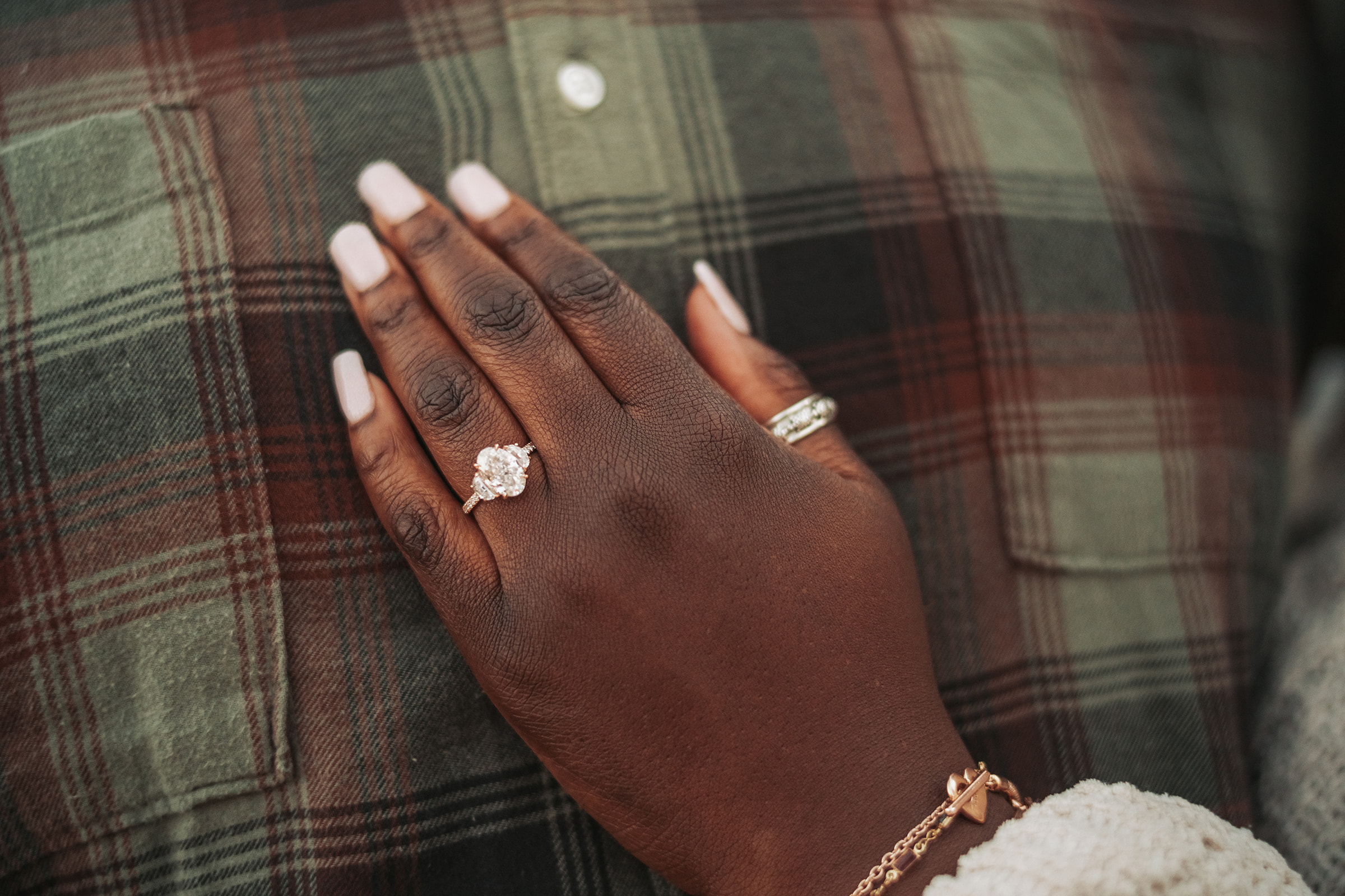 Close-up of engagement ring on hand with plaid fabric, golden hour lighting