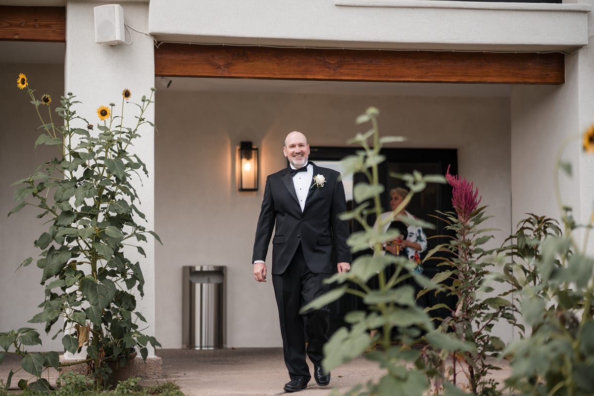 Carlos walks out past the sunflowers along the white walls of El Verde Inn