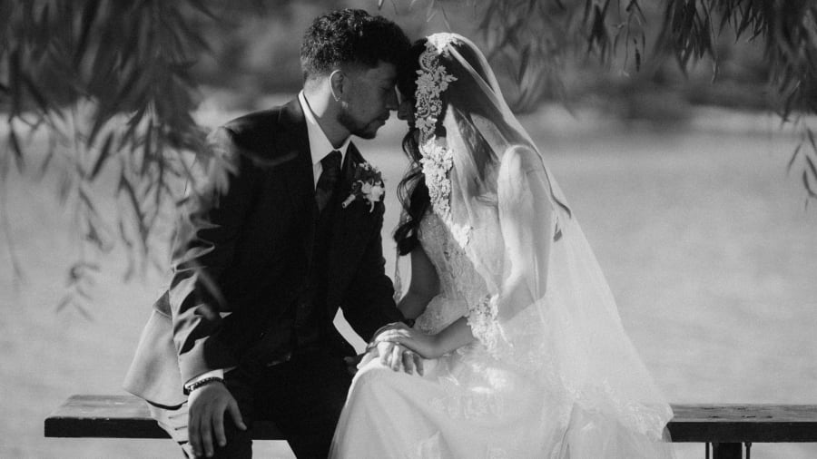 Black and white wedding kiss beside a stone wall