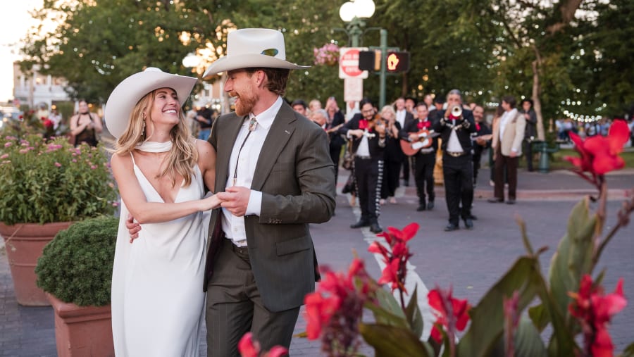 Newlyweds on the plaza with a mariachi band behind