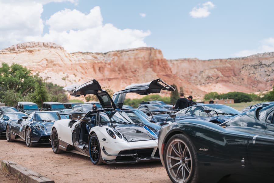 Pagani hypercars lined up under the red cliffs of Ghost Ranch