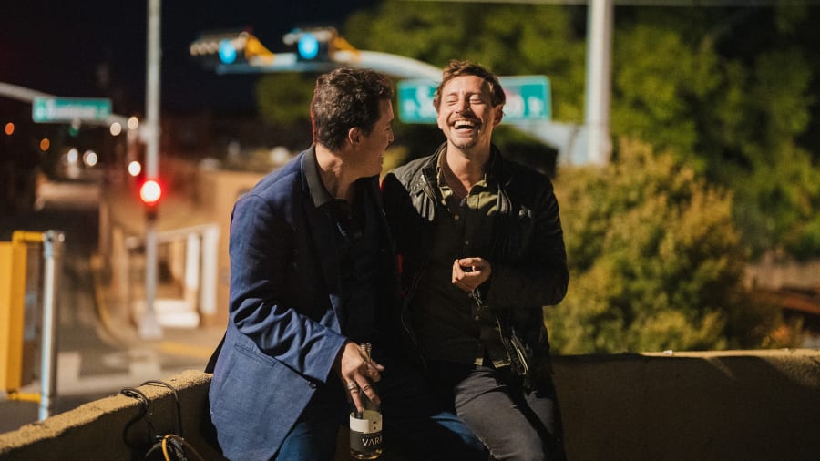 Two friends laughing on a rooftop at night
