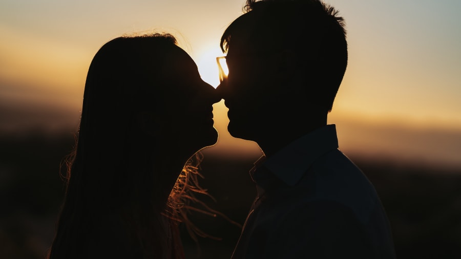 Couple in silhouette kissing at sunset