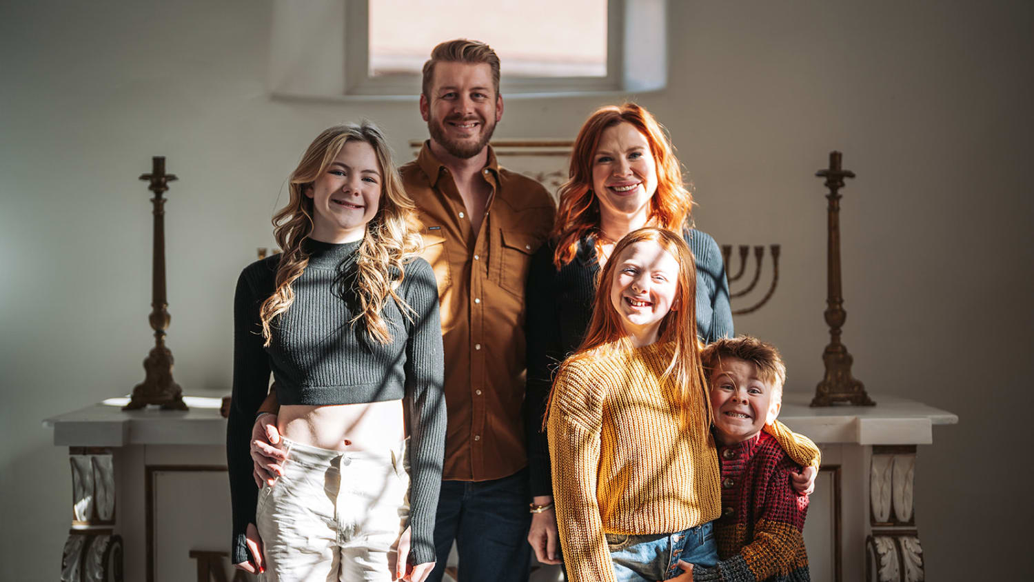 Bishops Lodge wedding photographer Santa Fe - This family portrait was taken indoors within a chapel or church setting, evidenced by the decorativ