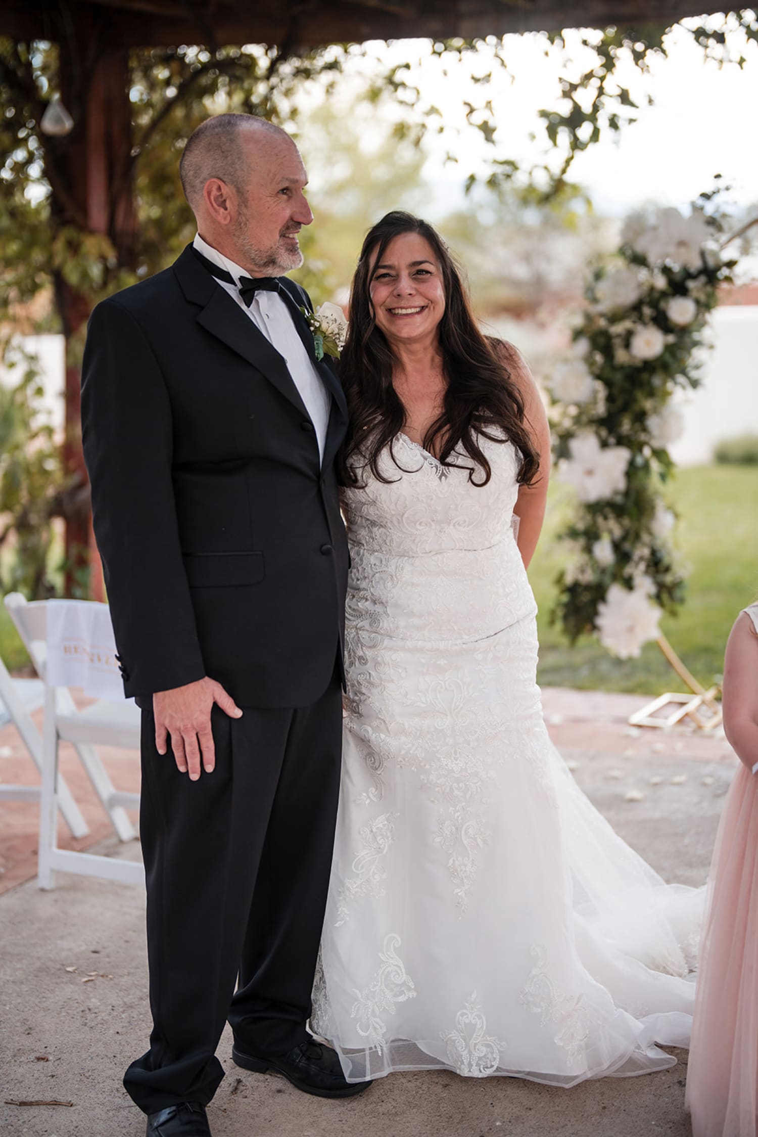 wedding ceremony captures a bride and groom standing beneath a rustic wooden pergola adorned with... — Casey Addason Photography