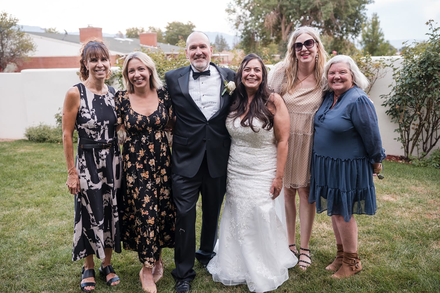 ceremony portrait captures the bride and groom with five family members in a manicured lawn setti... — Casey Addason Photography