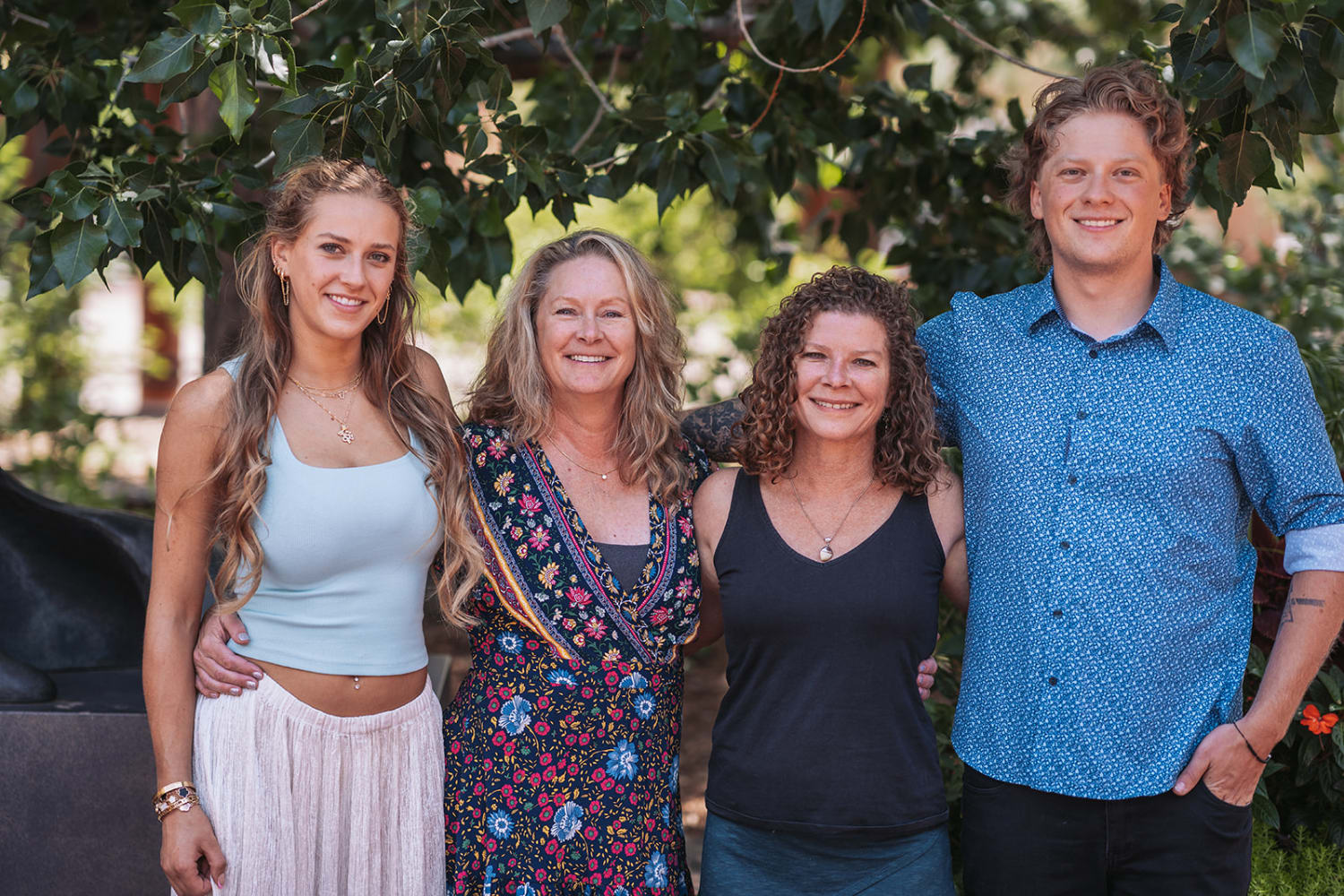 family portrait captures four subjects posed against lush green foliage and climbing vines in wha... — Casey Addason Photography