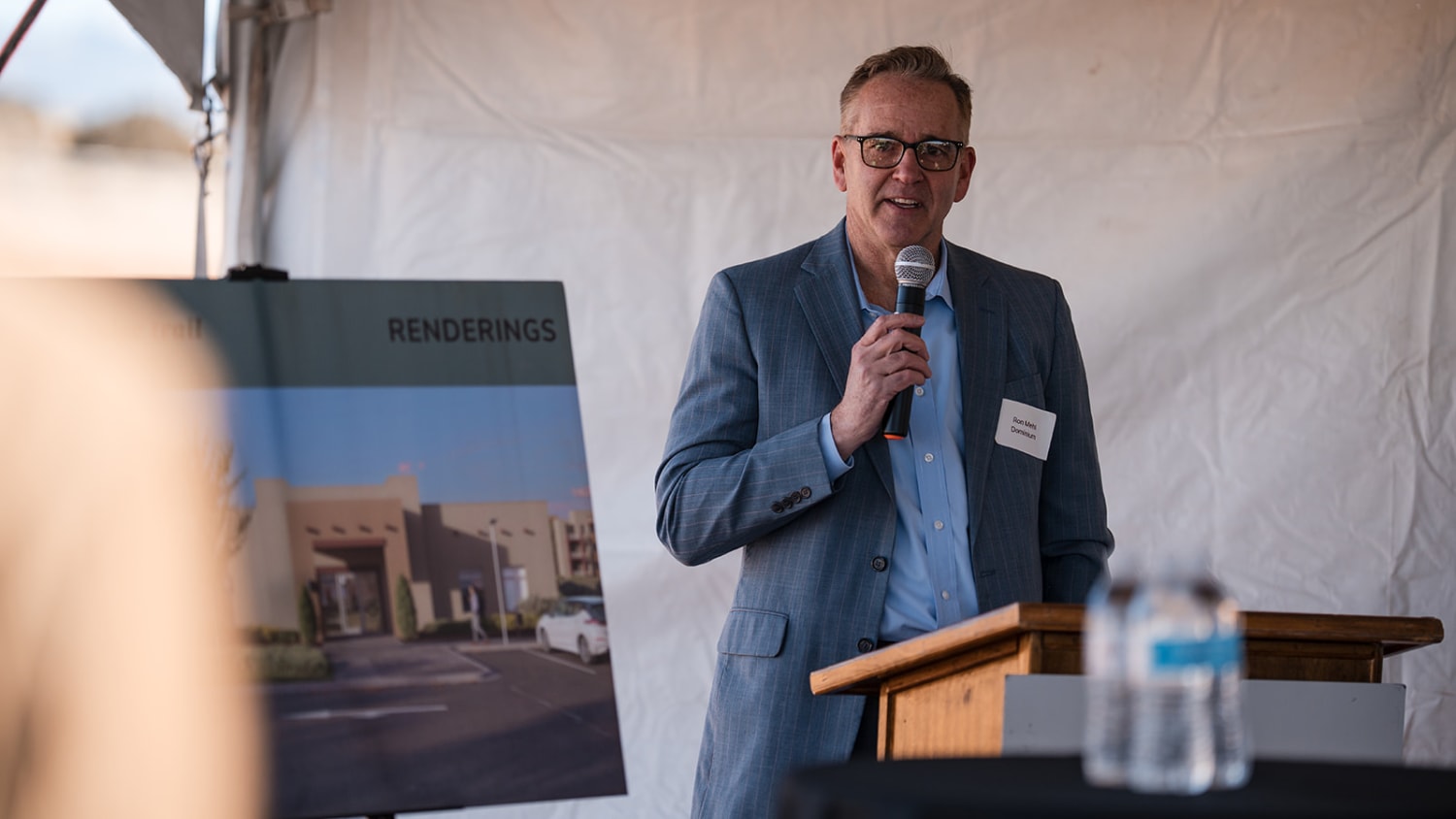 Executive presenting at podium with architectural renderings at Albuquerque groundbreaking - Casey Addason Photography