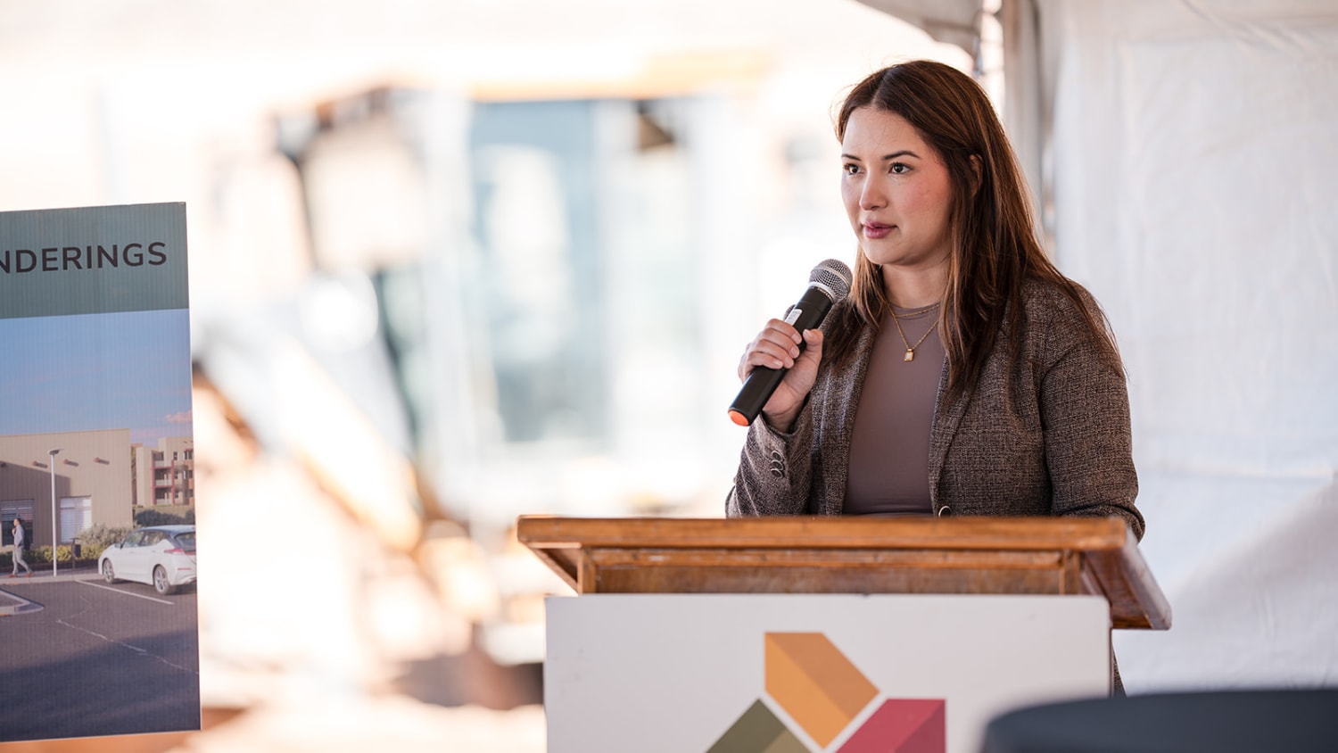 Woman presenting at podium in bright modern venue during Albuquerque corporate conference - Casey Addason Photography