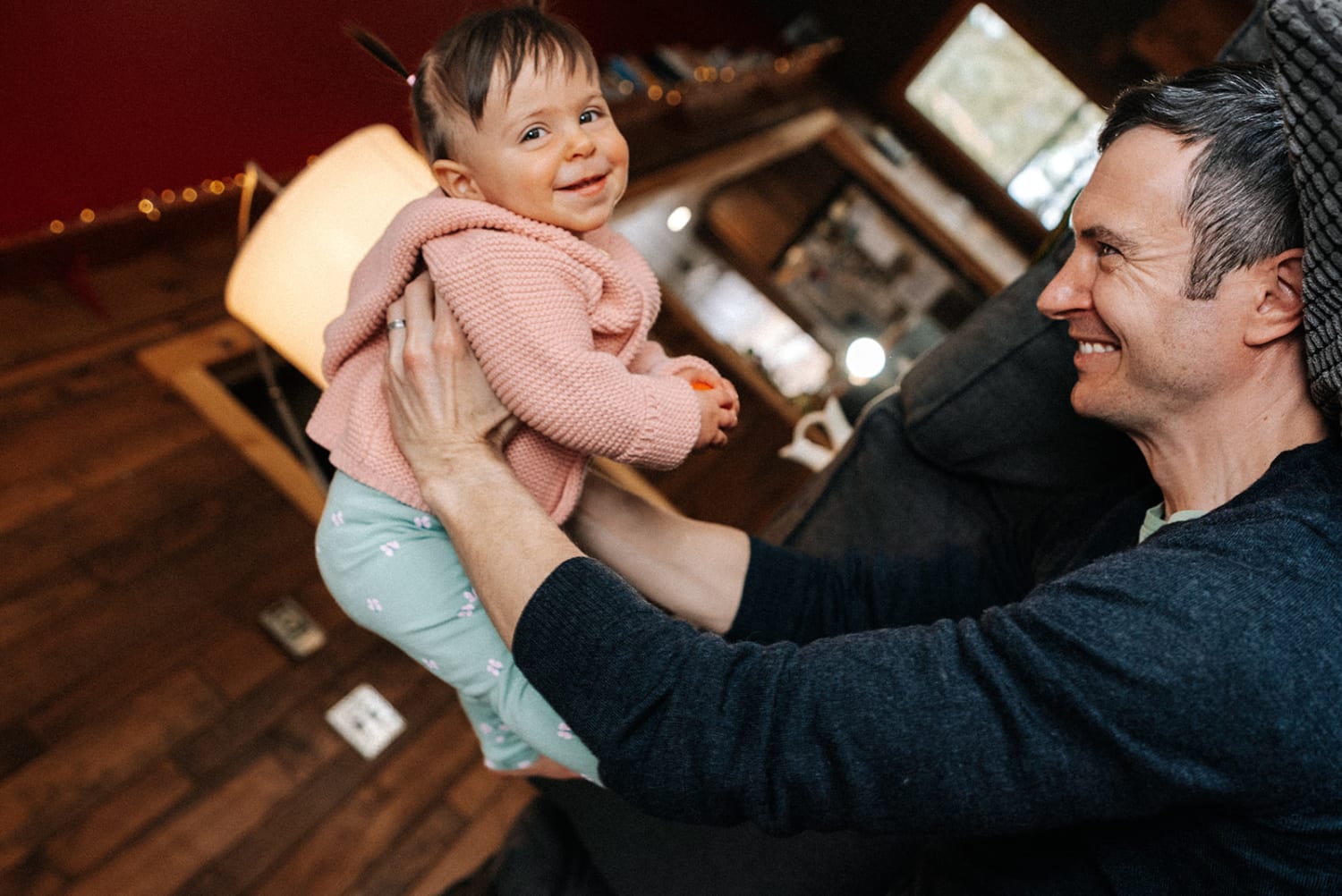This intimate indoor family portrait photographs a father holding his smiling toddler in what appears t — Casey Addason Photography