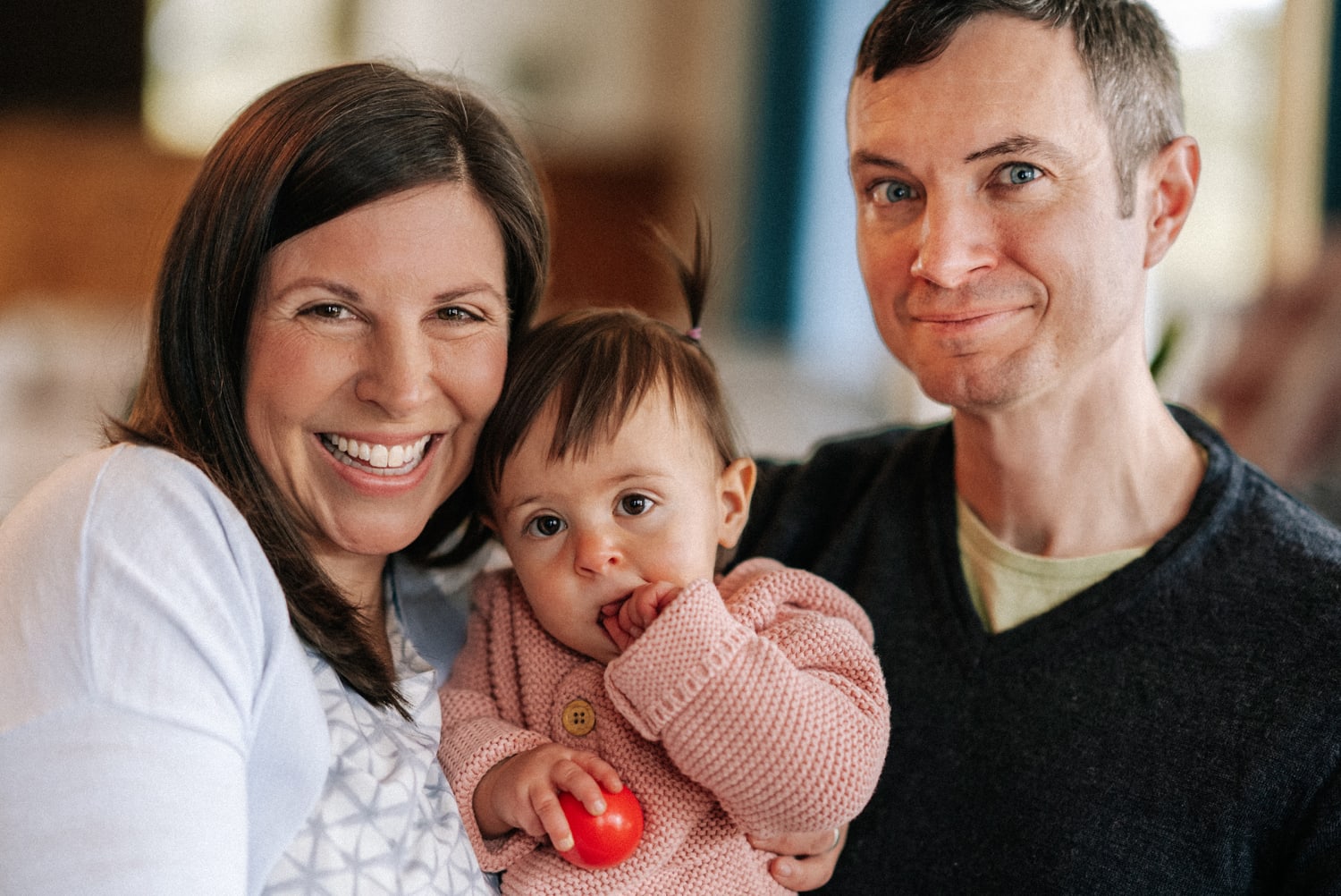 This indoor family portrait photographs three subjects—two adults and a toddler—in what appears to be a — Casey Addason Photography