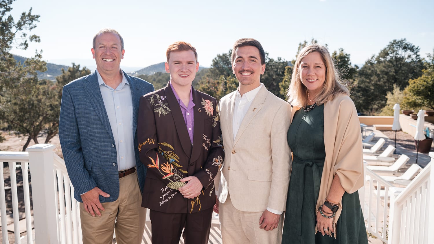 portrait captures four family members on a wooden deck railing with expansive views of forested m... — Casey Addason Photography