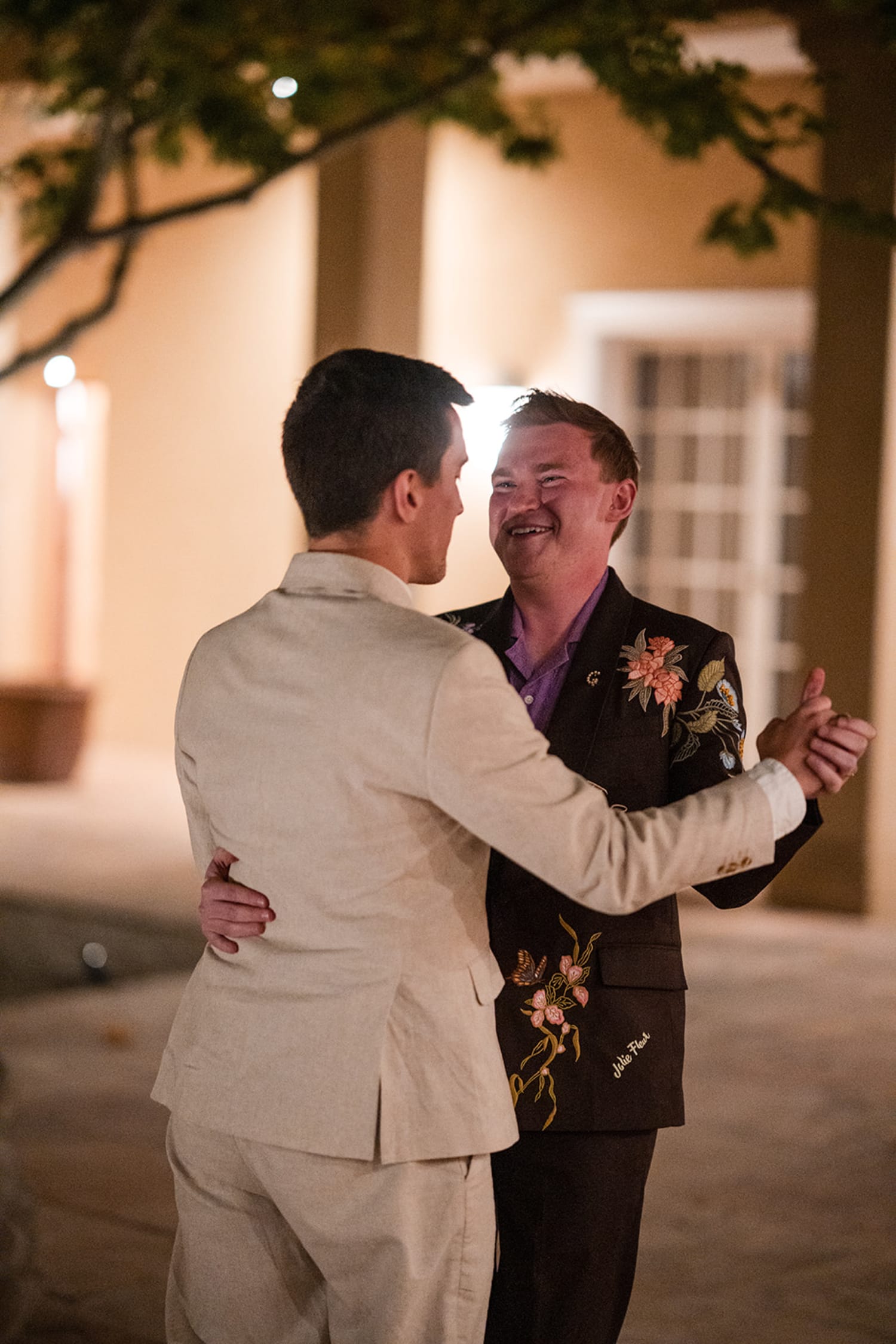 nighttime portrait captures two grooms in formal attire outside a Southwestern-style adobe buildi... — Casey Addason Photography