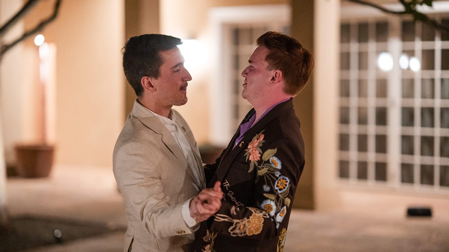 evening photograph captures two grooms in an elegant indoor courtyard setting, likely within a So... — Casey Addason Photography