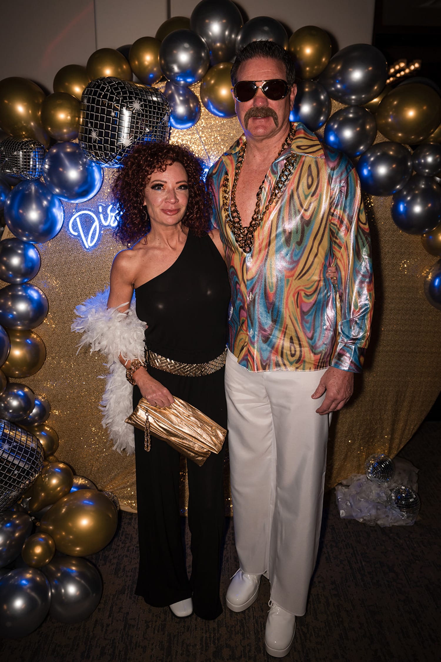 event photograph captures two guests posed against an elaborate balloon installation featuring go... — Casey Addason Photography