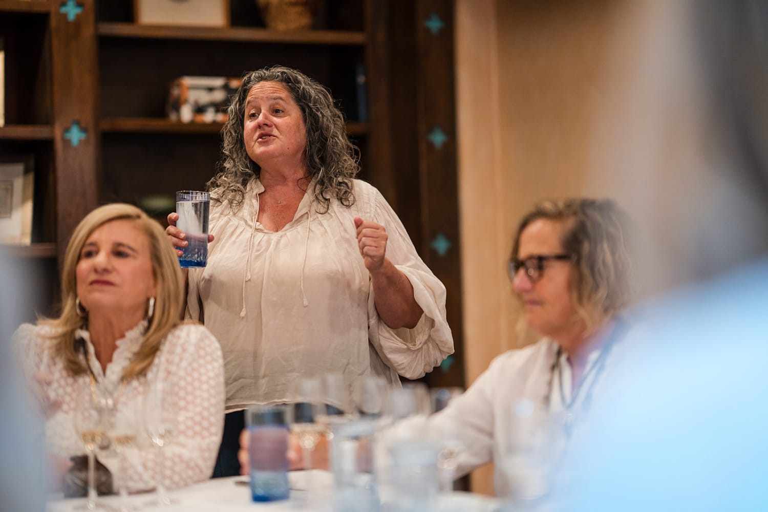 gathering takes place in a contemporary venue featuring warm wood cabinetry with turquoise decora... — Casey Addason Photography