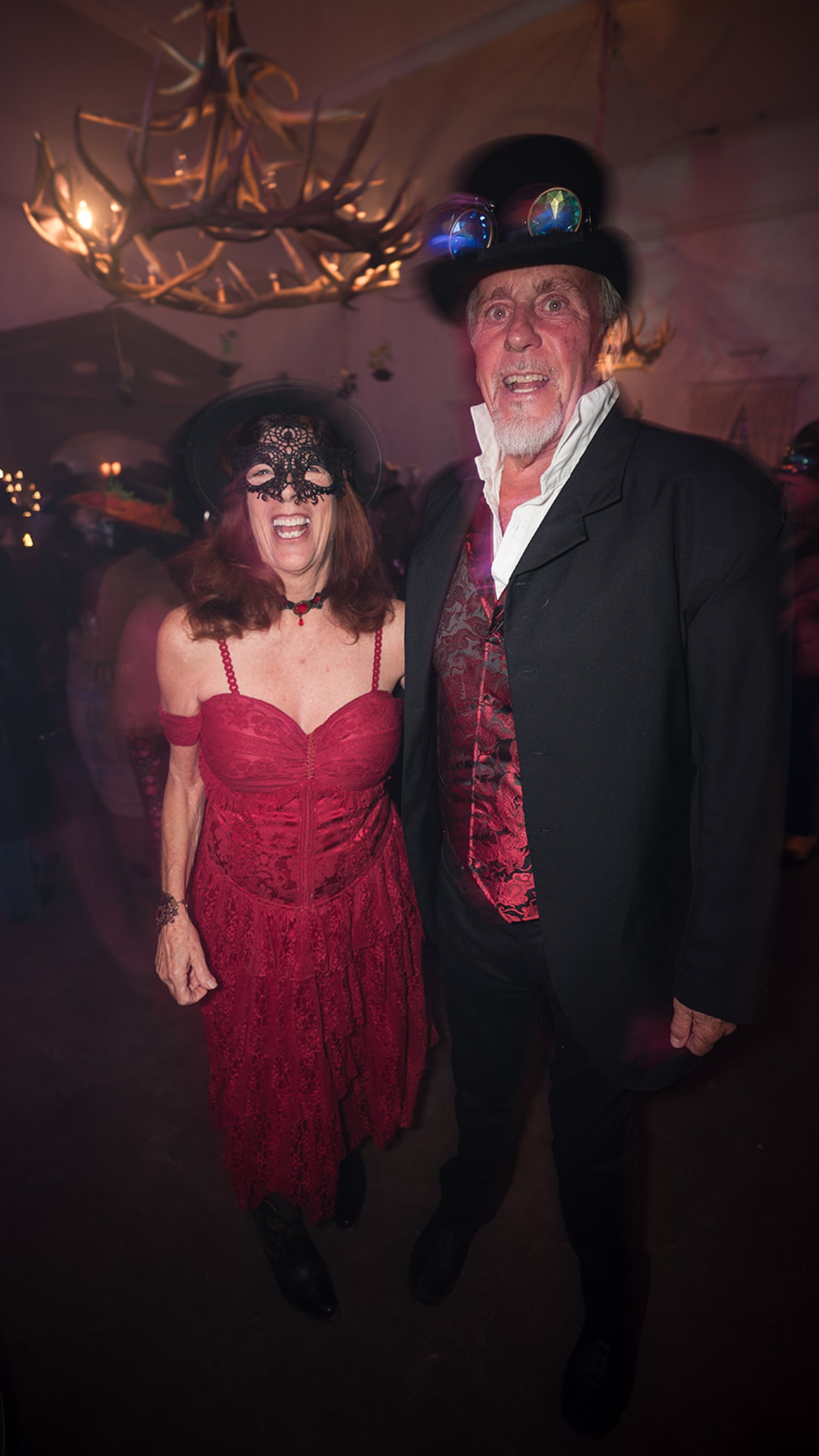 evening event features two guests in elaborate costume attire posed beneath an ornate branching c... — Casey Addason Photography