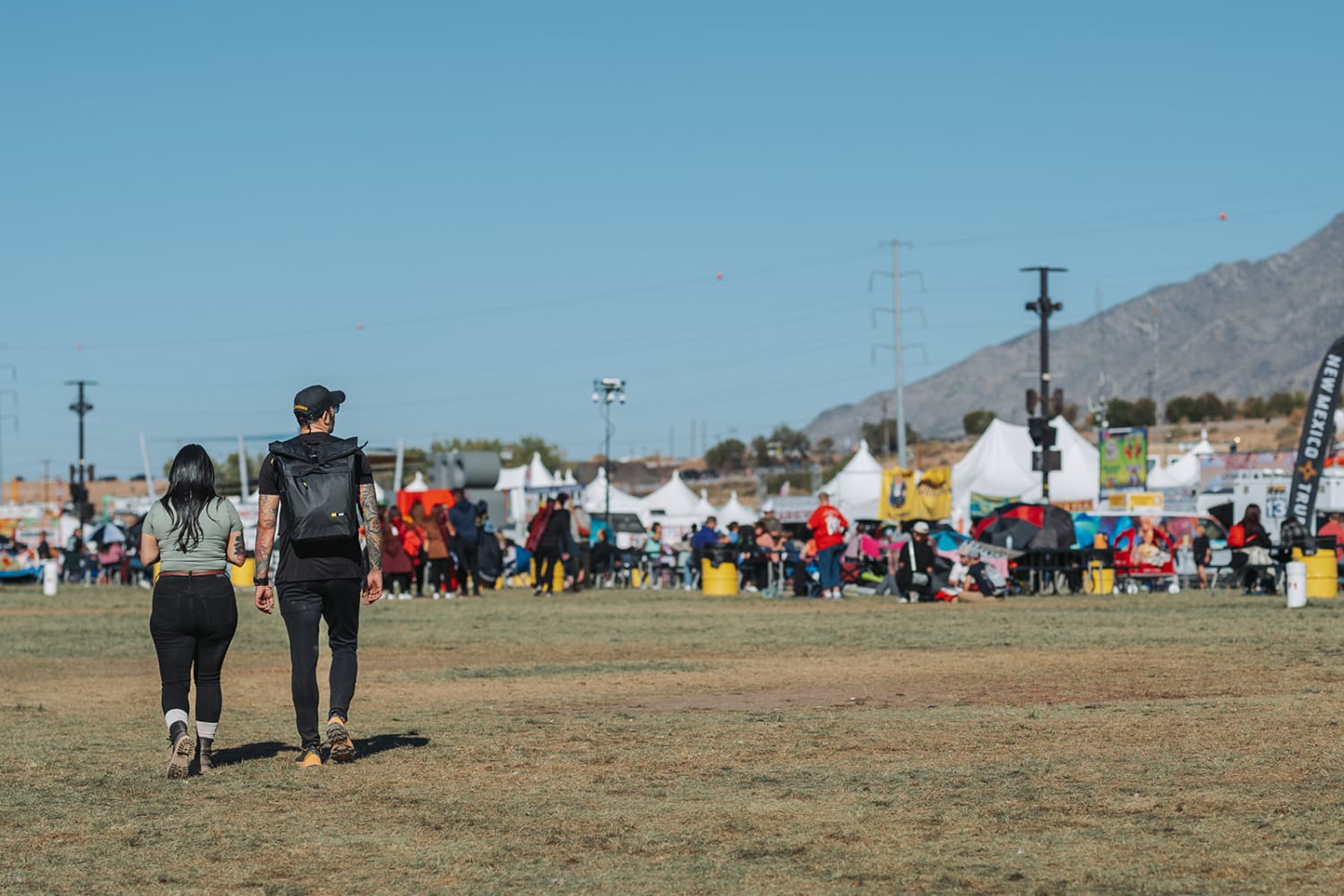 festival scene documents two visitors jogging across an expansive dirt field during clear  — Casey Addason Photography