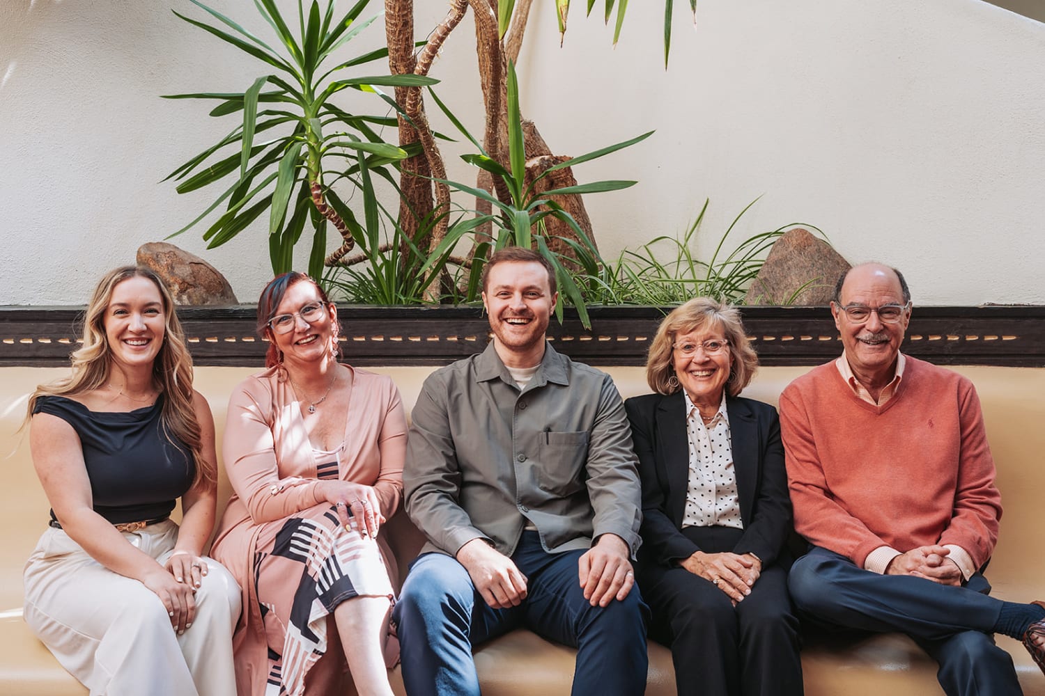 portrait captures five people seated together against a neutral beige wall with a decorative hori... — Casey Addason Photography