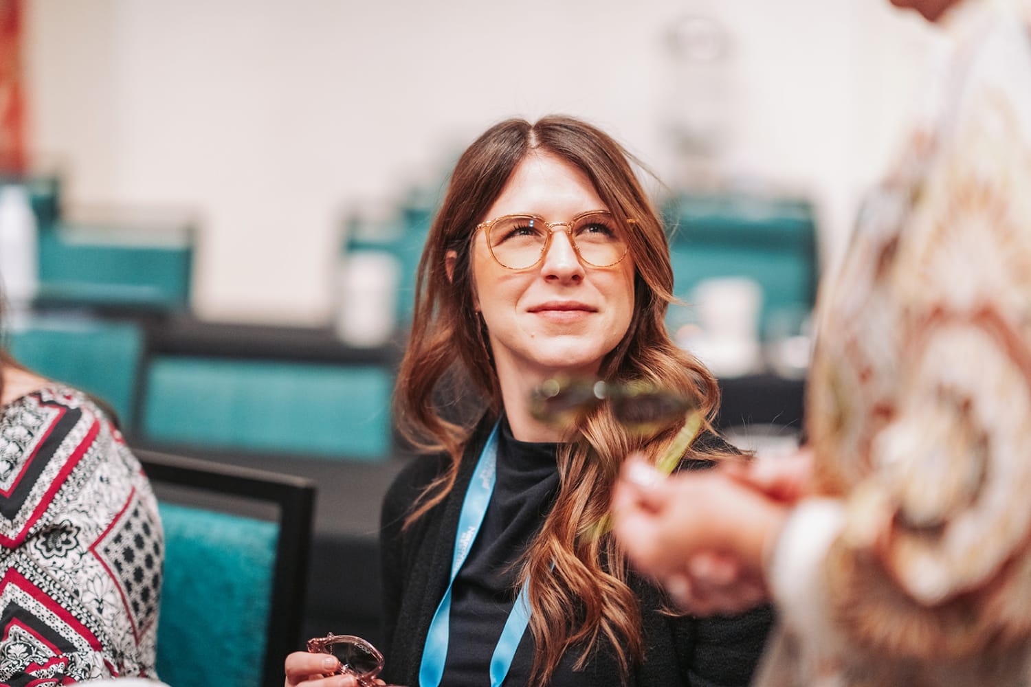 event photograph captures a woman wearing glasses and a blue lanyard at what appears to be a conf... — Casey Addason Photography