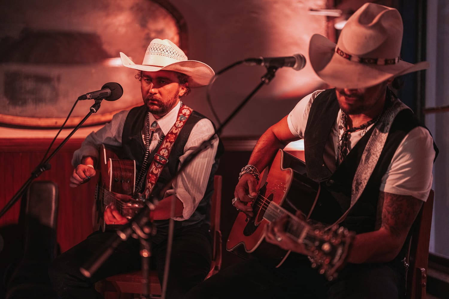 Two musicians perform at an intimate indoor venue bathed in warm, dramatic red-orange ambient lig... — Casey Addason Photography