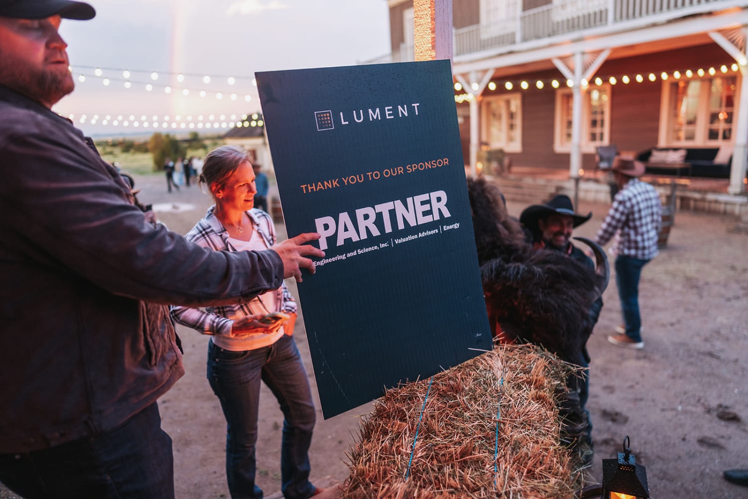 evening event takes place at a rustic venue featuring Western-style architecture with red barn st... — Casey Addason Photography