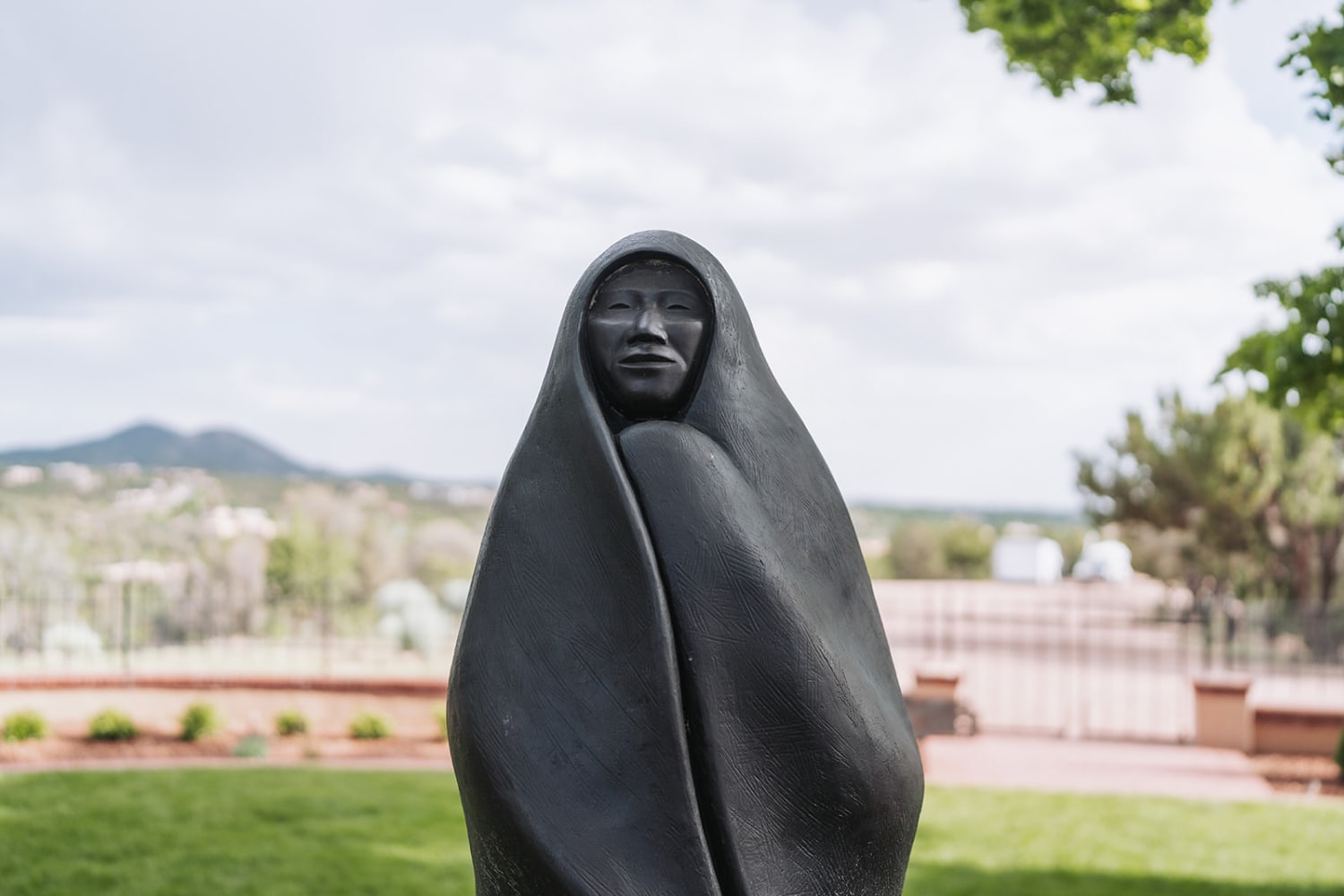 photograph captures a striking black stone sculpture displayed in an outdoor garden setting, like... — Casey Addason Photography