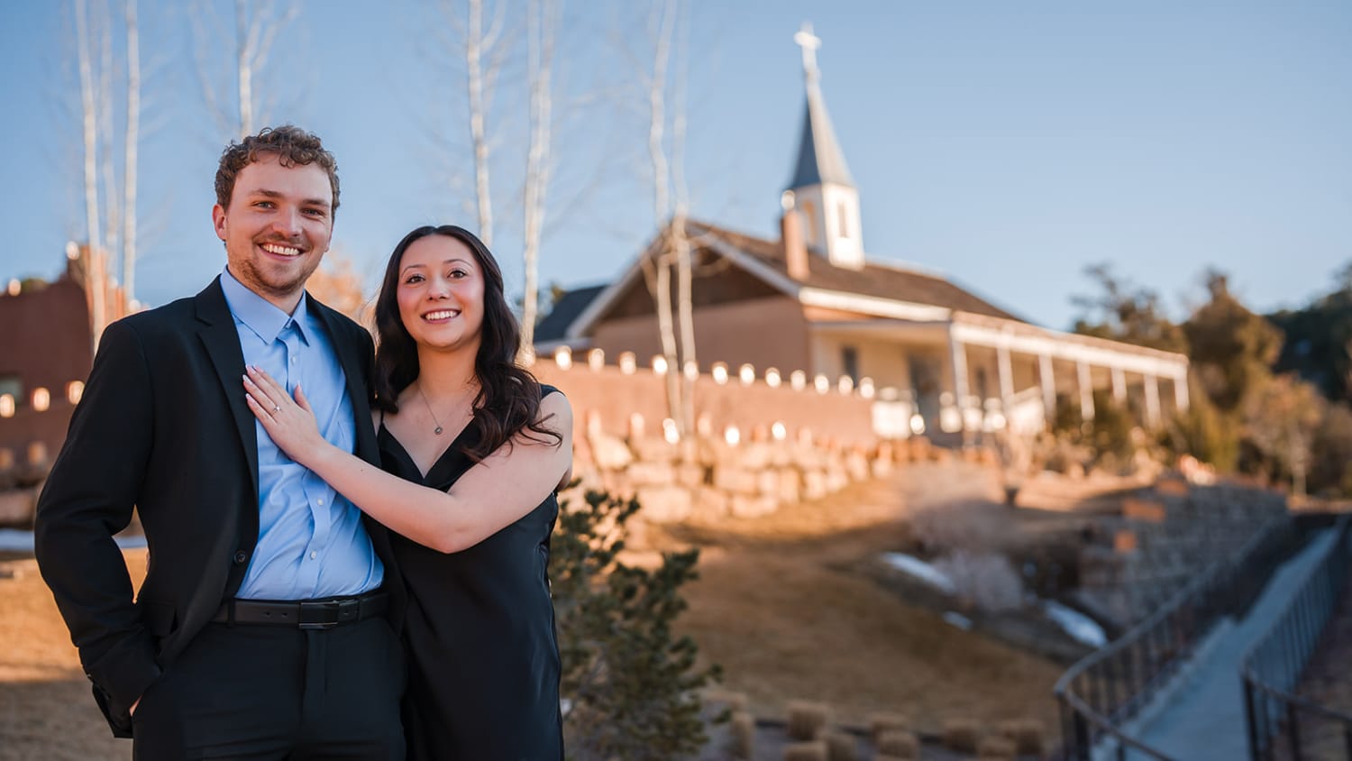 Engagement couple at brick chapel with white steeple in Santa Fe, golden hour light, bare birch trees, Casey Addason Photography