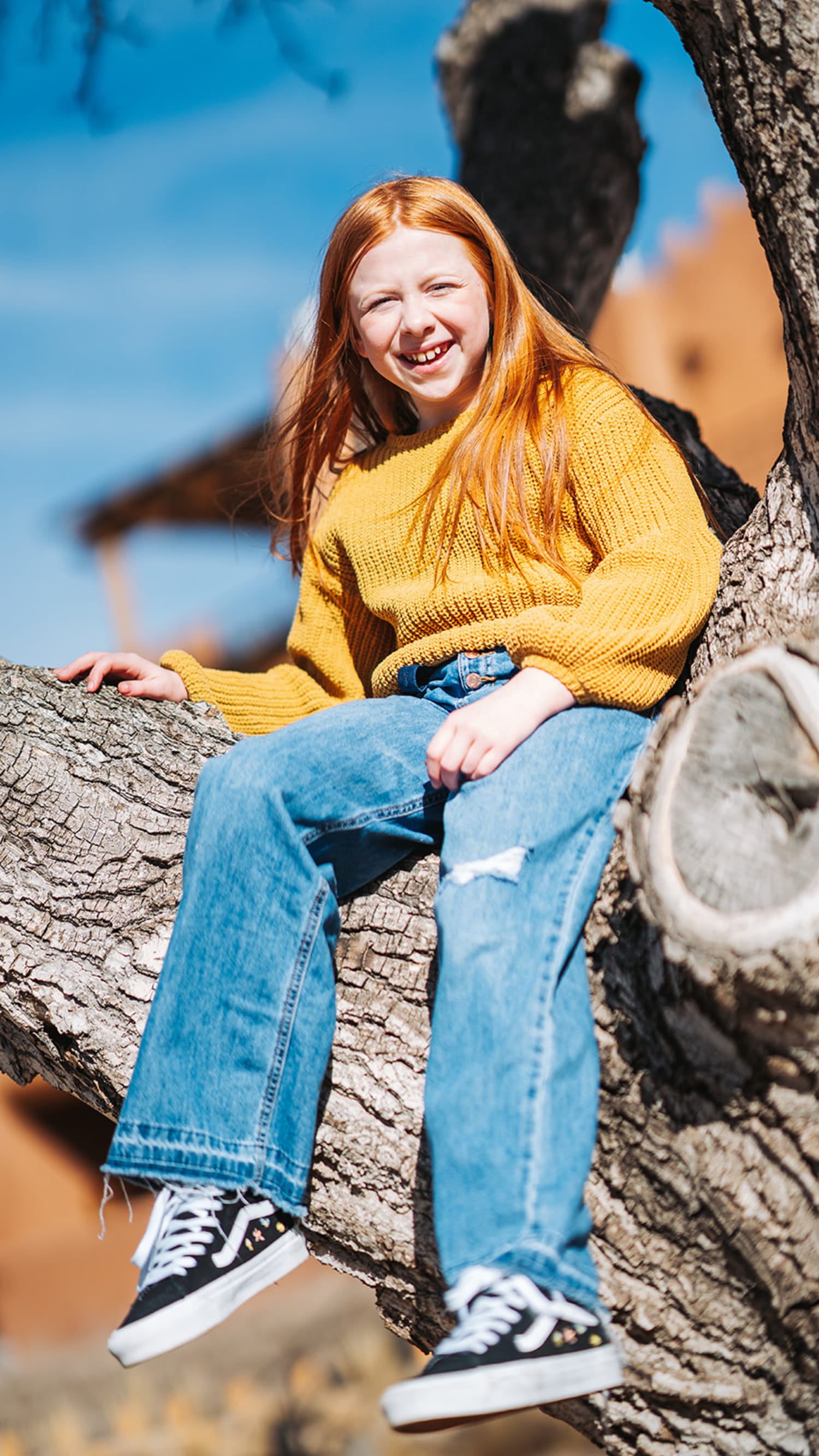 portrait documents a young subject seated on a tree branch against a clear blue sky and warm, sand... — Casey Addason Photography