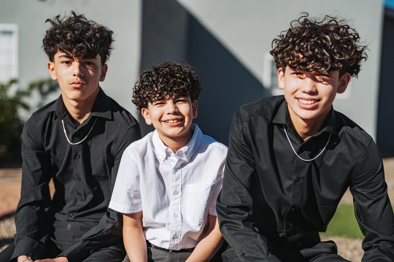 portrait documents three young men posed against a modern white stucco building with geometric arc... — Casey Addason Photography