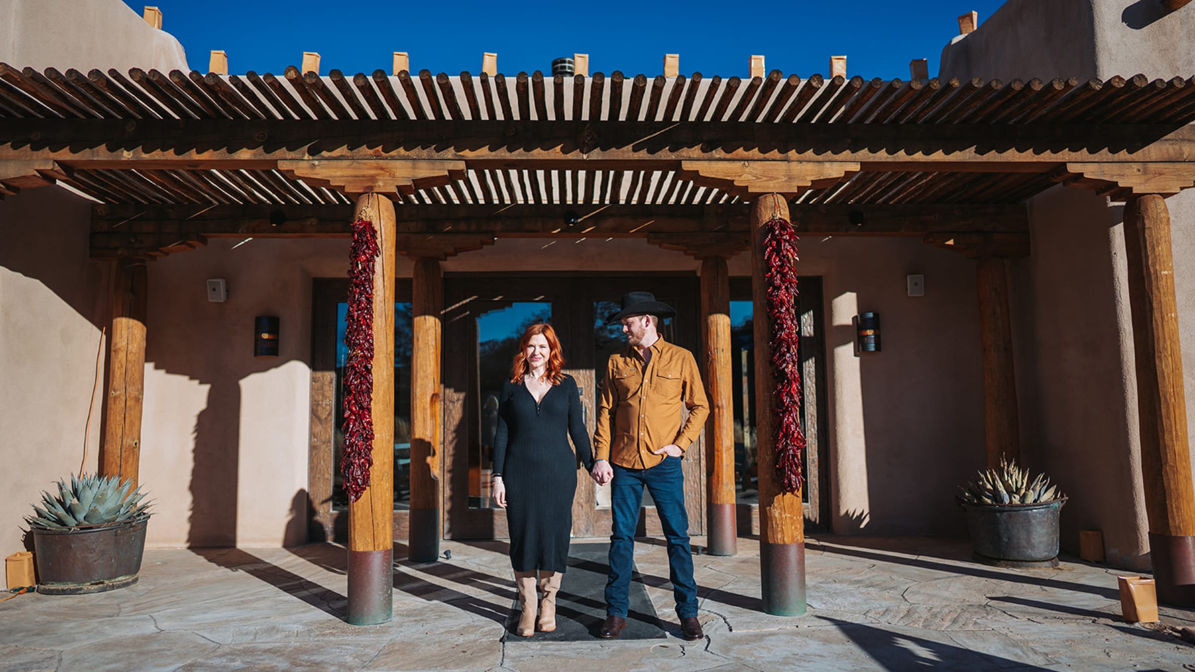 Engagement portrait with golden light against adobe architecture and chile ristras