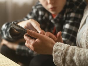 Aikuinen ja lapsi katsovat yhdessä älypuhelinta; molemmat keskittyvät näyttöön ja osoittavat sitä sormellaan.