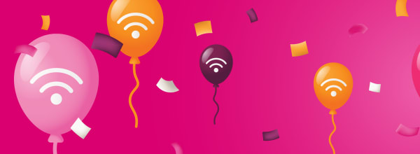 Värikkäitä ilmapalloja, joissa on Wi-Fi-symboleja ja konfetteja kirkkaan vaaleanpunaisella taustalla.