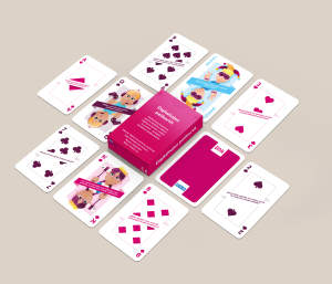 Omituisilla kuvilla ja tekstillä koristeltu pelikorttisetti vaaleanpunaisen laatikon ympärille beigellä taustalla.