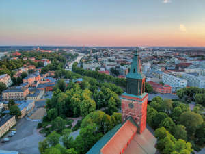 Ilmakuva kaupungista, jossa on suuri kirkko, vihreitä puita ja rakennuksia auringonlaskun aikaan.