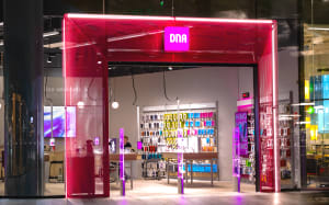 Värikäs DNA-myymälä, jossa on kirkkaanpunainen sisäänkäynti, esittelypöydät ja puhelinlisävarusteita seinillä.