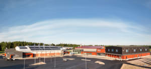 Nykyaikainen koulutuskampus, jossa on aurinkopaneelit ja jota ympäröi metsä kirkkaan sinisen taivaan alla.