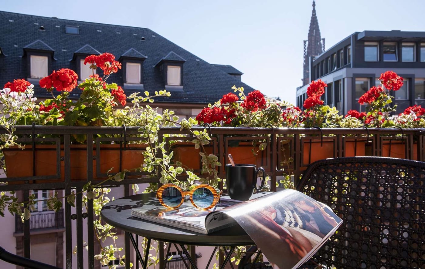 A flowered balcony of the Maison Rouge with a view of the cathedral spire