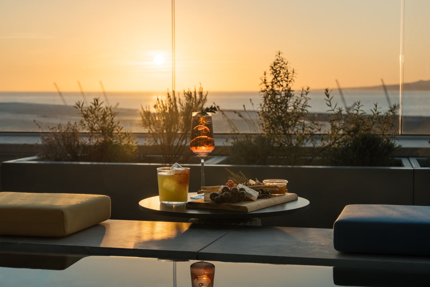 Cocktails and appetizer platter on the rooftop of the Ruby Lilou hotel at sunset over the sea