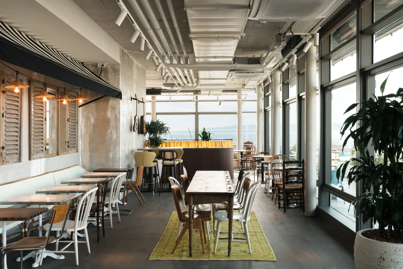 Bar room of the Ruby Lilou hotel with mismatched chairs, antique shutters and large windows open to the port