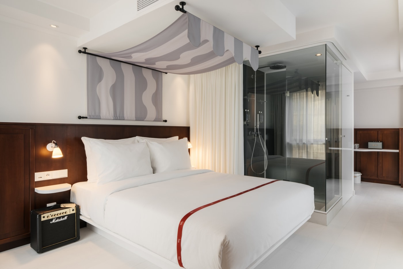Lovely room of the Ruby Lilou hotel with striped canopy, glass shower and Marshall amp