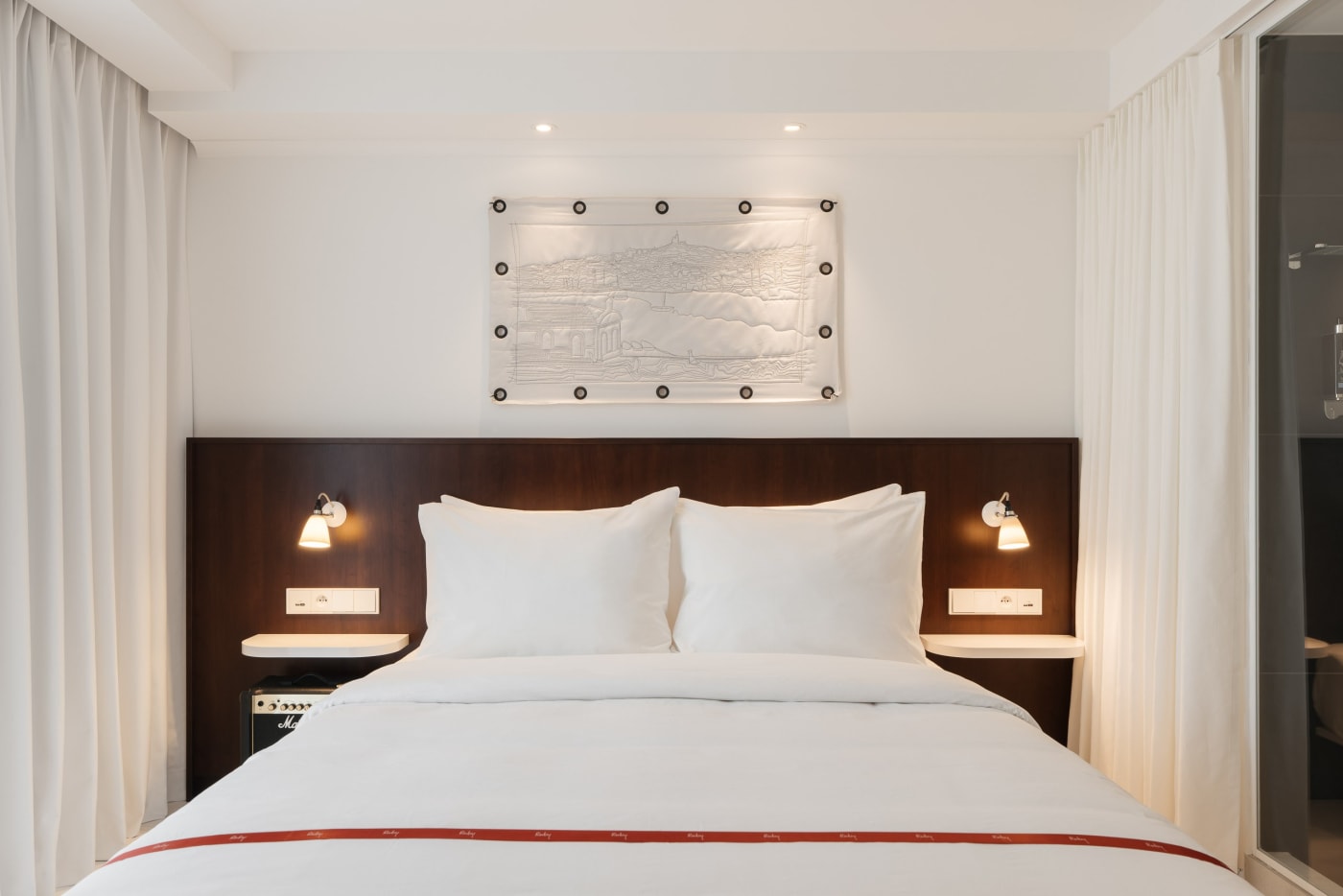 Cosy room of the Ruby Lilou hotel, large white bed, dark wood headboard and light curtains