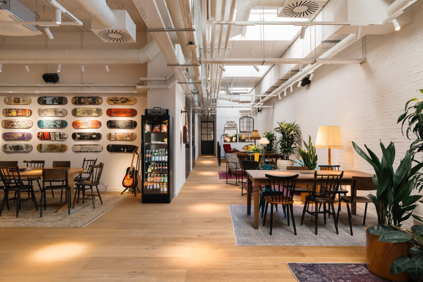 Common area of the Ruby Yani coworking in Marseille with wooden tables, plants and a wall of skateboards