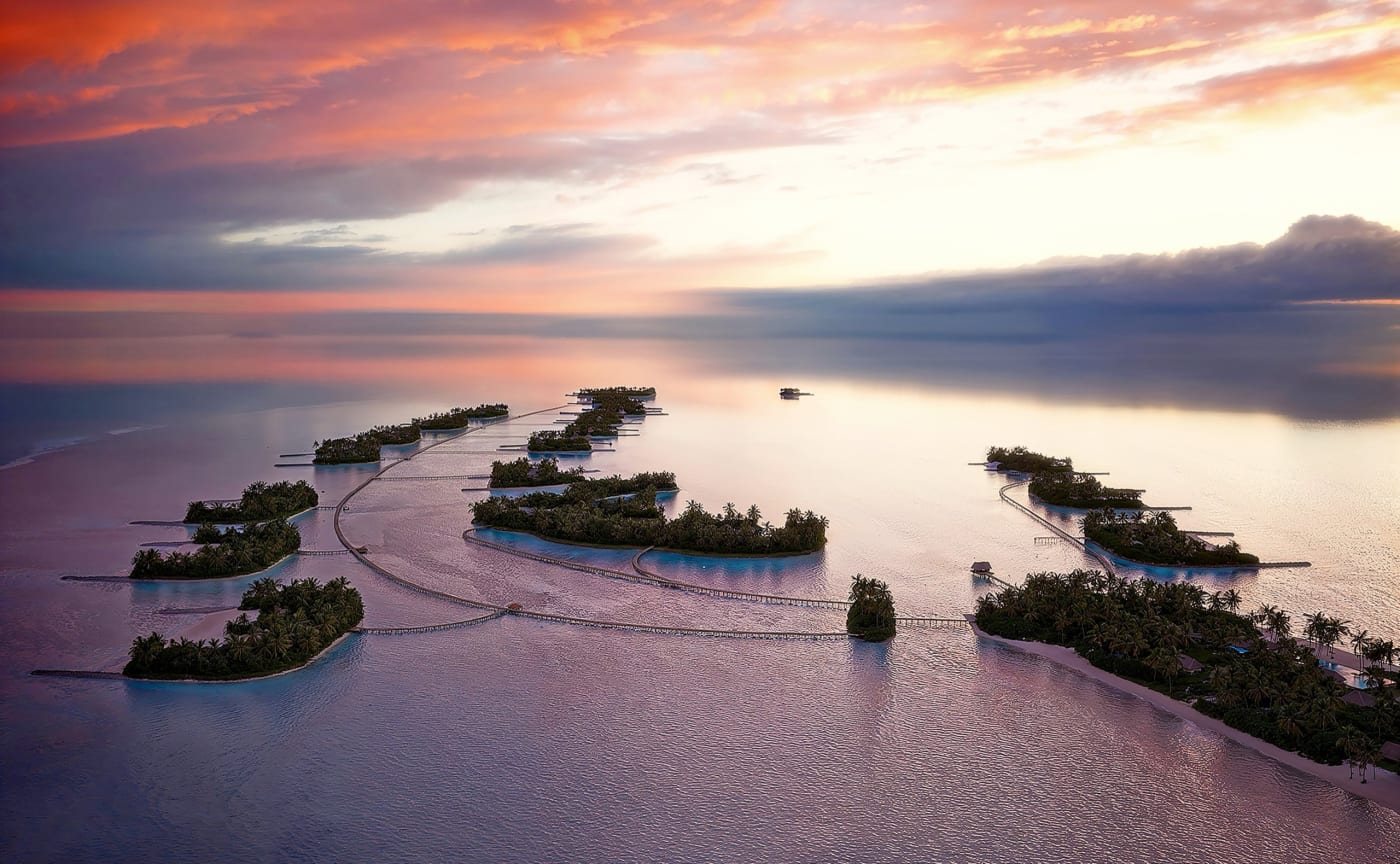 Luftbild-Rendering der durch Stege verbundenen Inseln von Amanolu im Vaavu-Atoll auf den Malediven bei Sonnenuntergang
