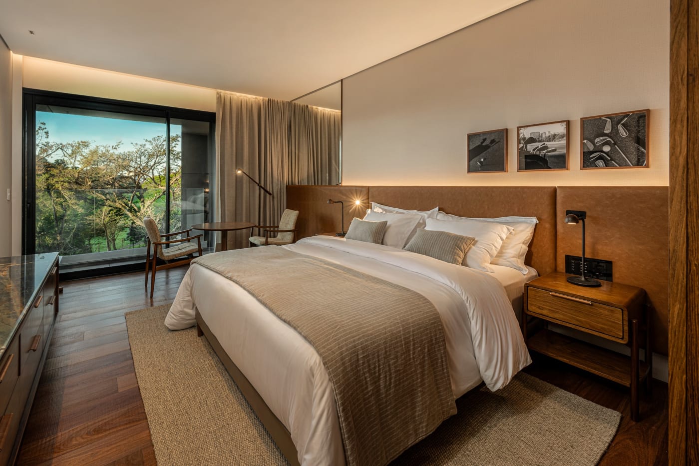 Chambre de The Almer Porto Alegre, bois naturel, baie vitrée sur la végétation du Country Club